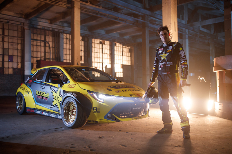 Fredric Aasbo stands with his 2019 Toyota Corolla hatchback Champion Formula DRIFT car