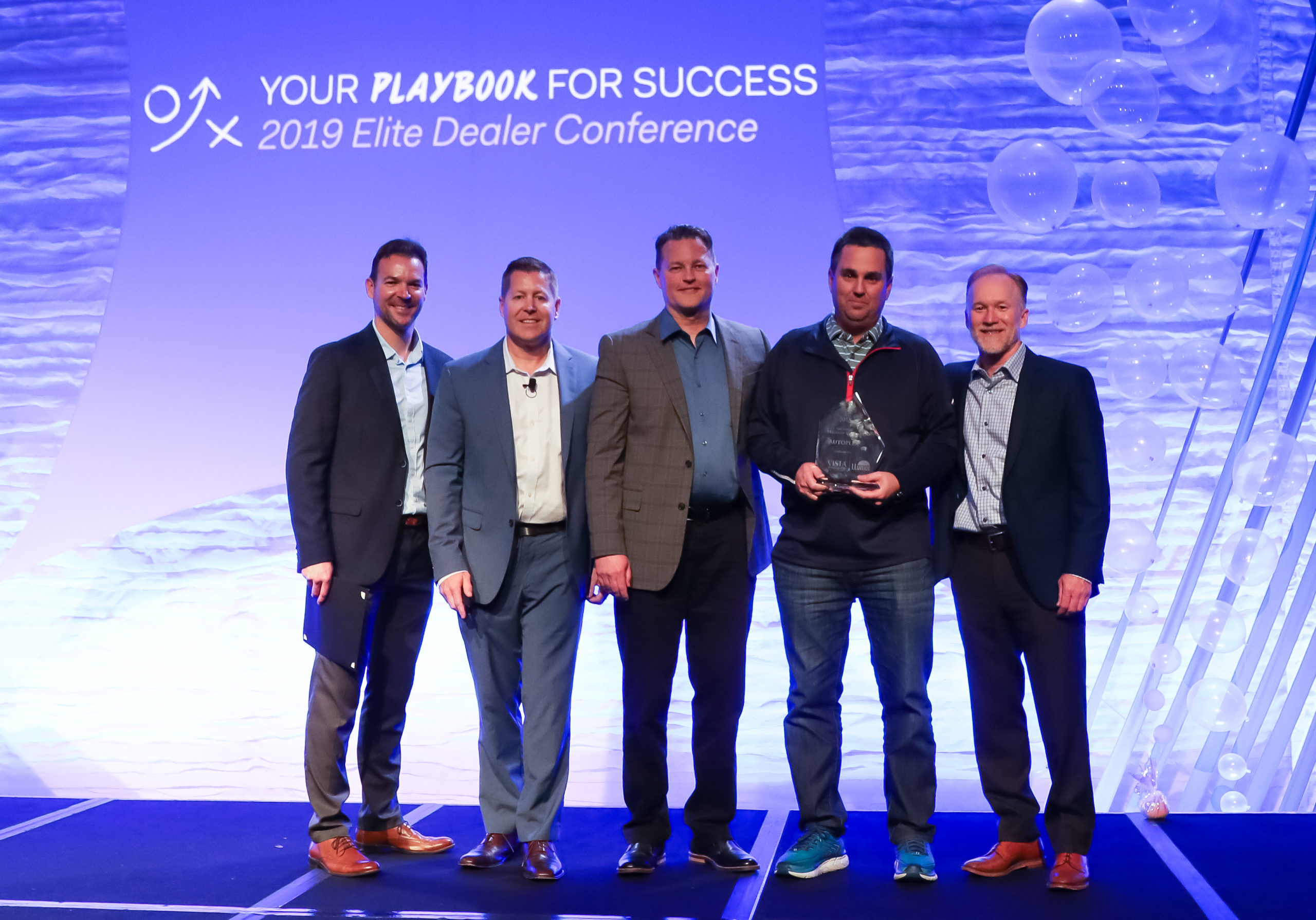 Josh Elliott (second from right), owner of Autoplex of Loveland, accepts the National Dealer of the Year award from Eastman Perf