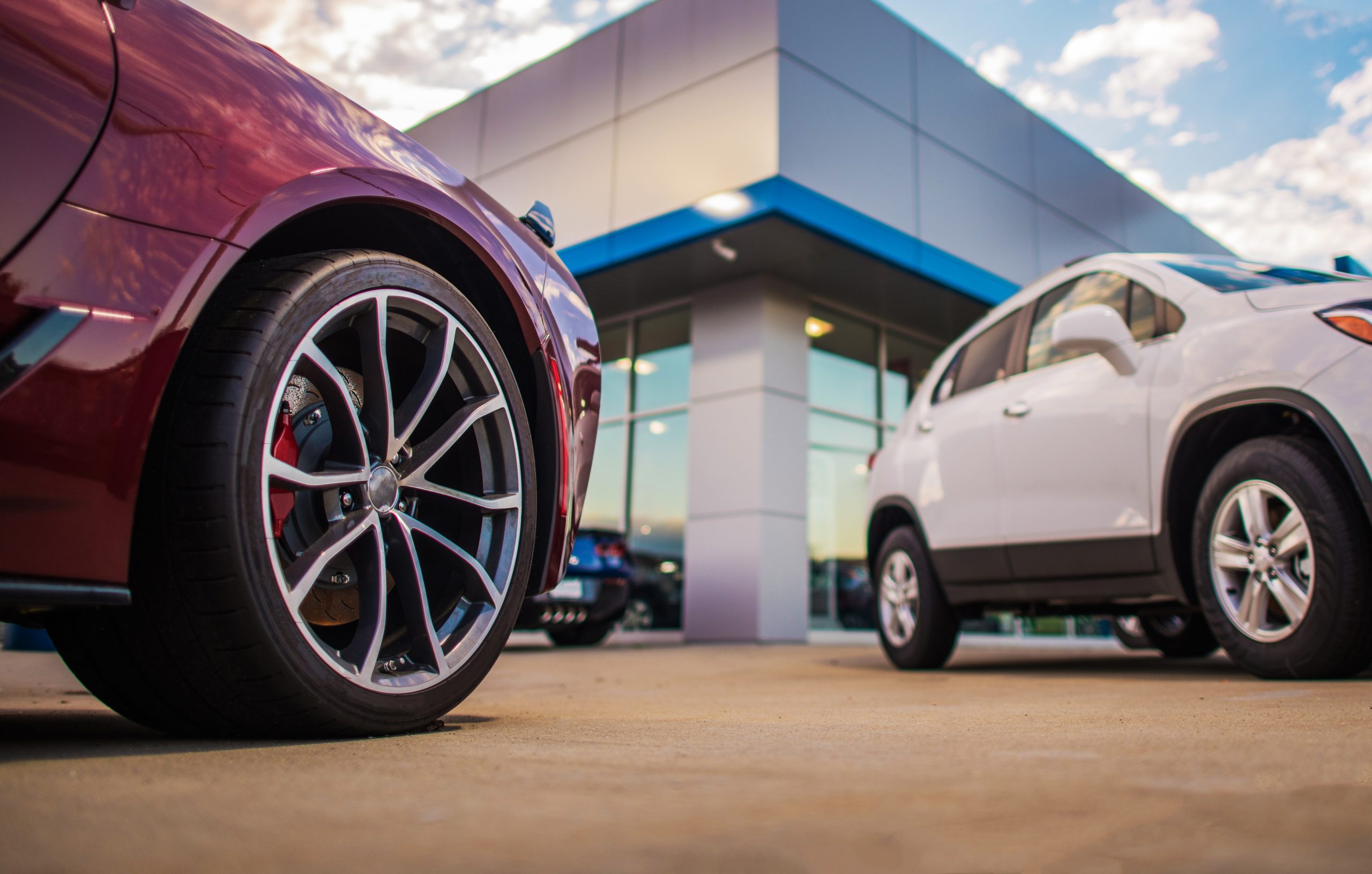 Automotive Dealership Store. New and Pre Owned Vehicles in Front of the Showroom Building.