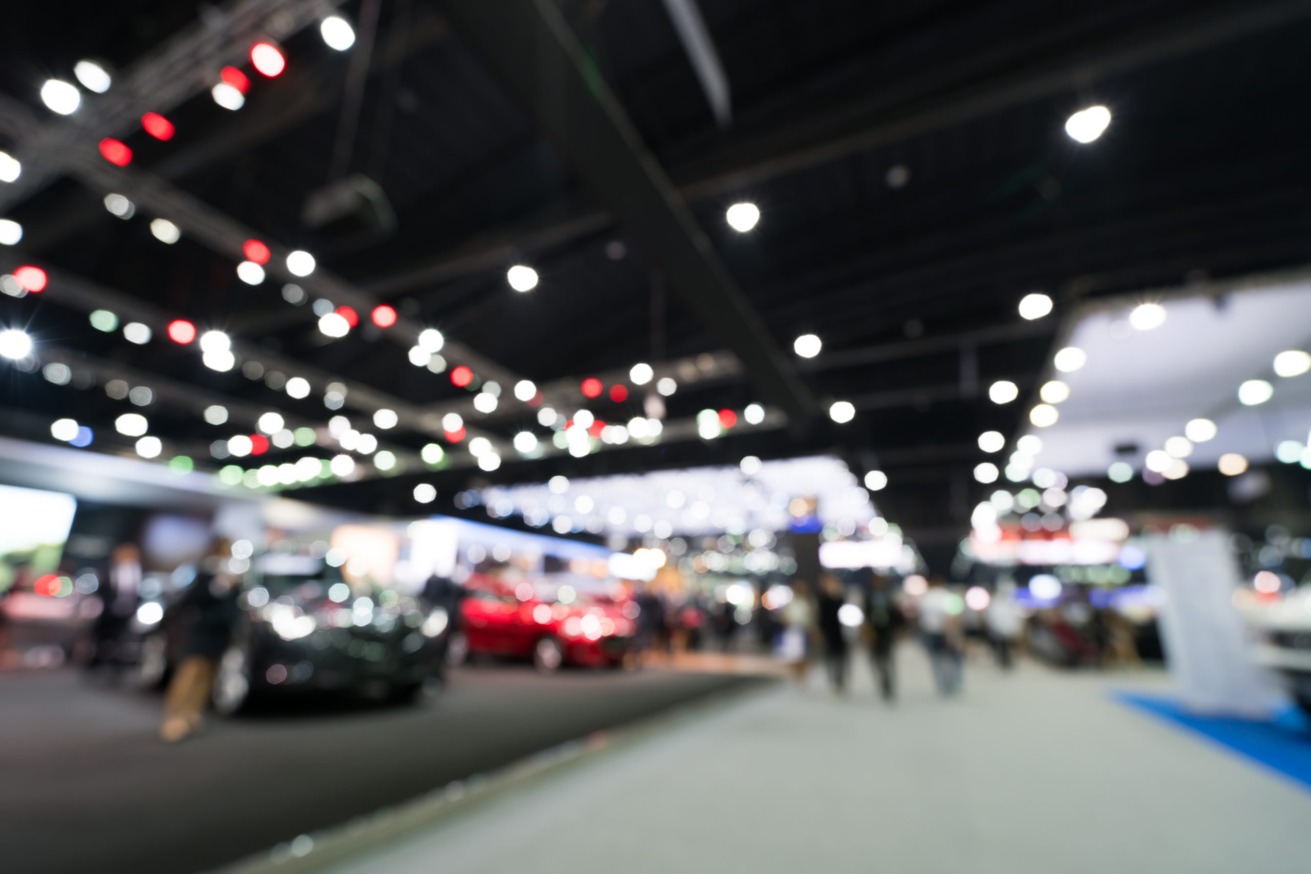 Blurred, defocused background of public event exhibition hall showing cars and automobiles, business commercial event concept