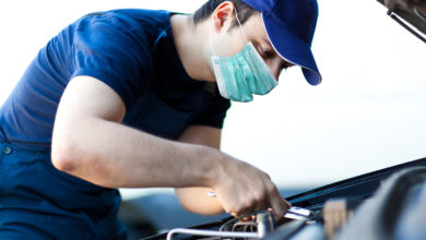 Mechanic fixing a car engine wearing a mask, coronavirus concept