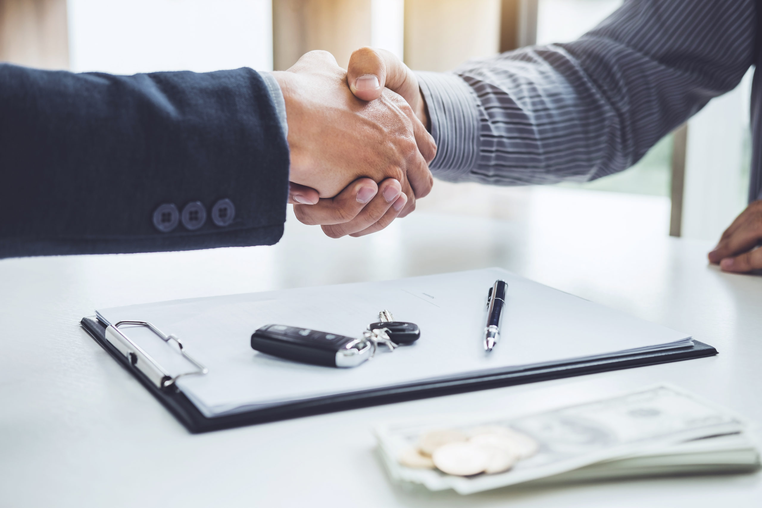 Handshake of cooperation customer and salesman after agreement, successful car loan contract buying or selling new vehicle.