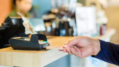 Hand put credit card In slot of credit card reader with blurry cashier at counter service, credit card payment, buy and sell products & service, the concept of payment without cash, selective focus.