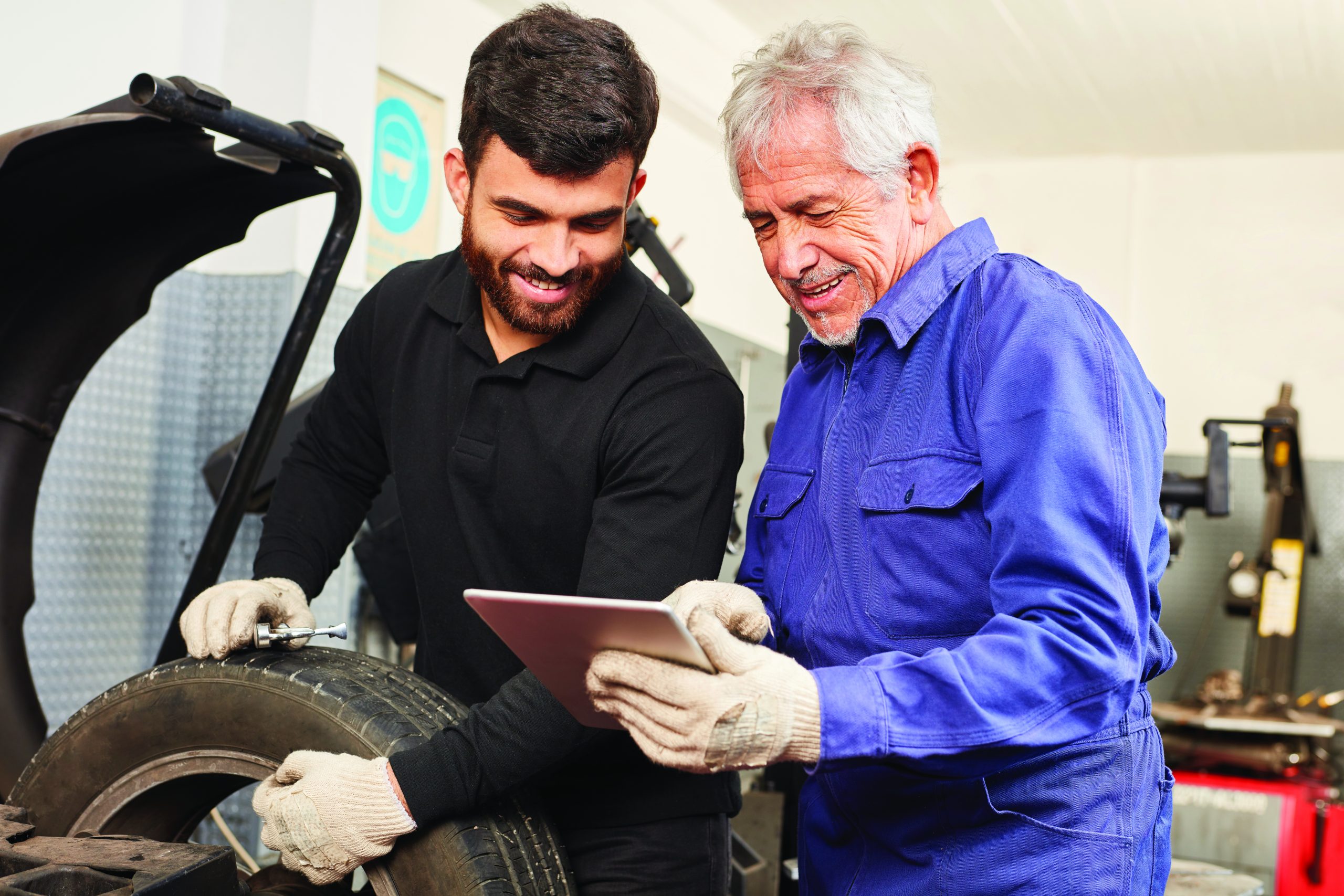 KFZ Meister als Ausbilder mit Mechatroniker Lehrling bei Fehler Diagnose mit Tablet PC