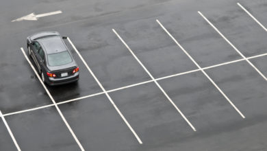 Single car in otherwise empty parking lot, in the rain
