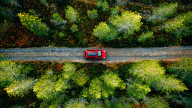 Aerial view of red car for traveling with a roof rack on a country road in Finland
