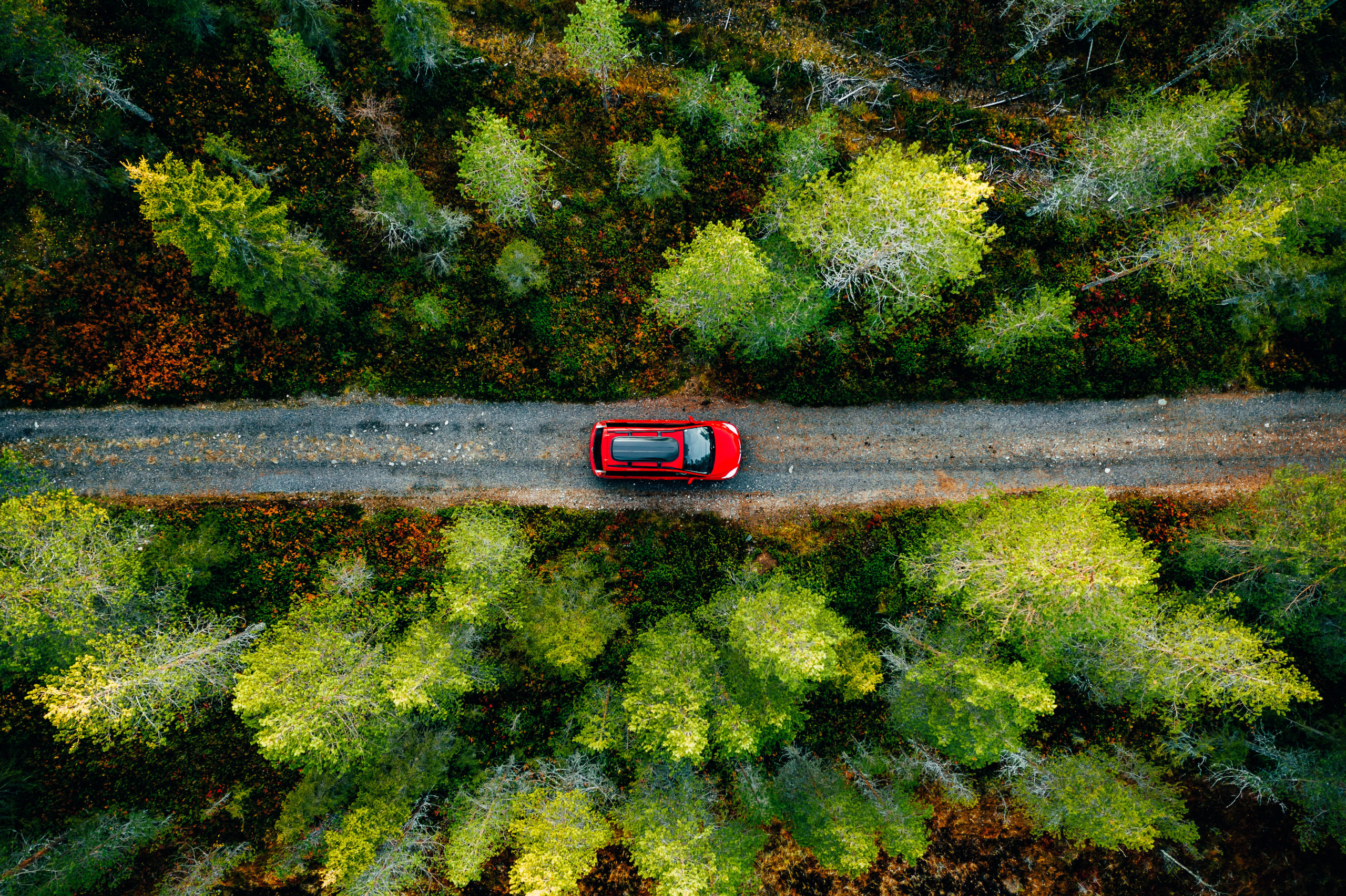 Aerial view of red car for traveling with a roof rack on a country road in Finland