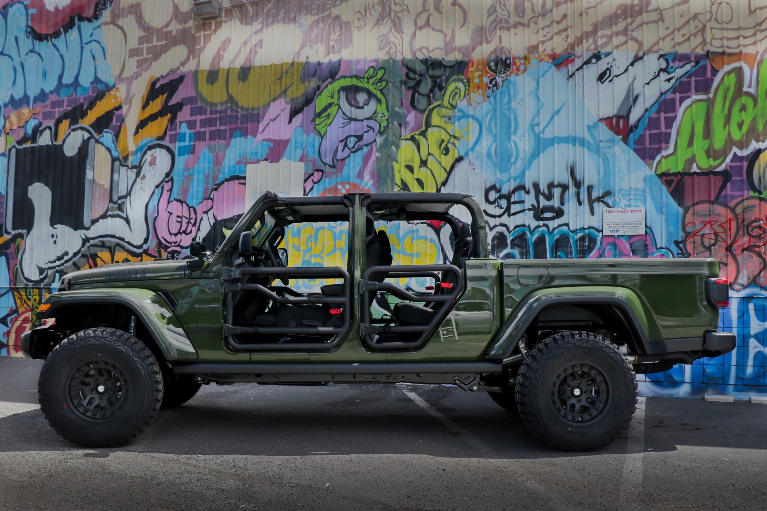 green modified truck in front of graffiti wall