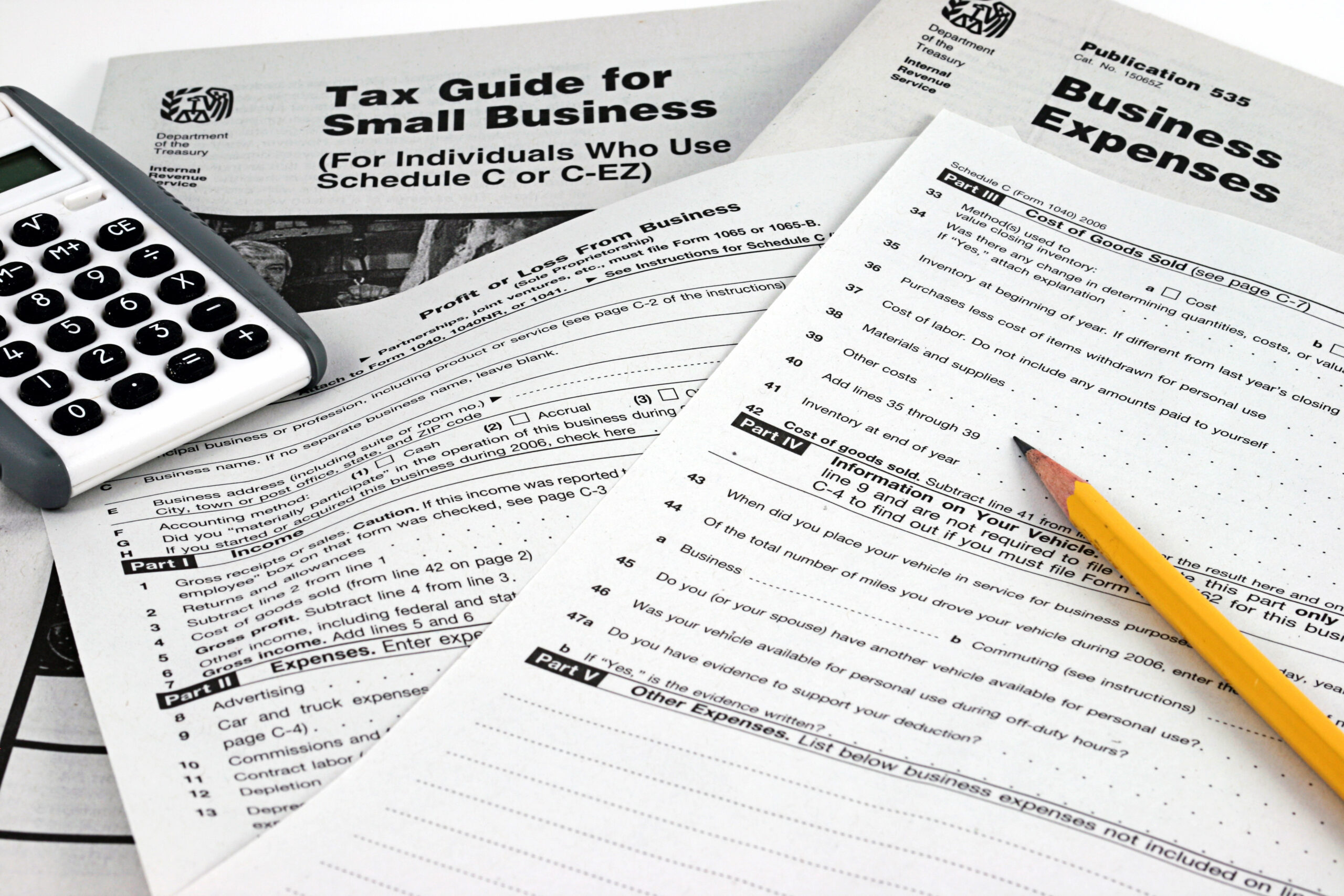 IRS Business Tax forms, business expense form and instructions with pencil and calculator