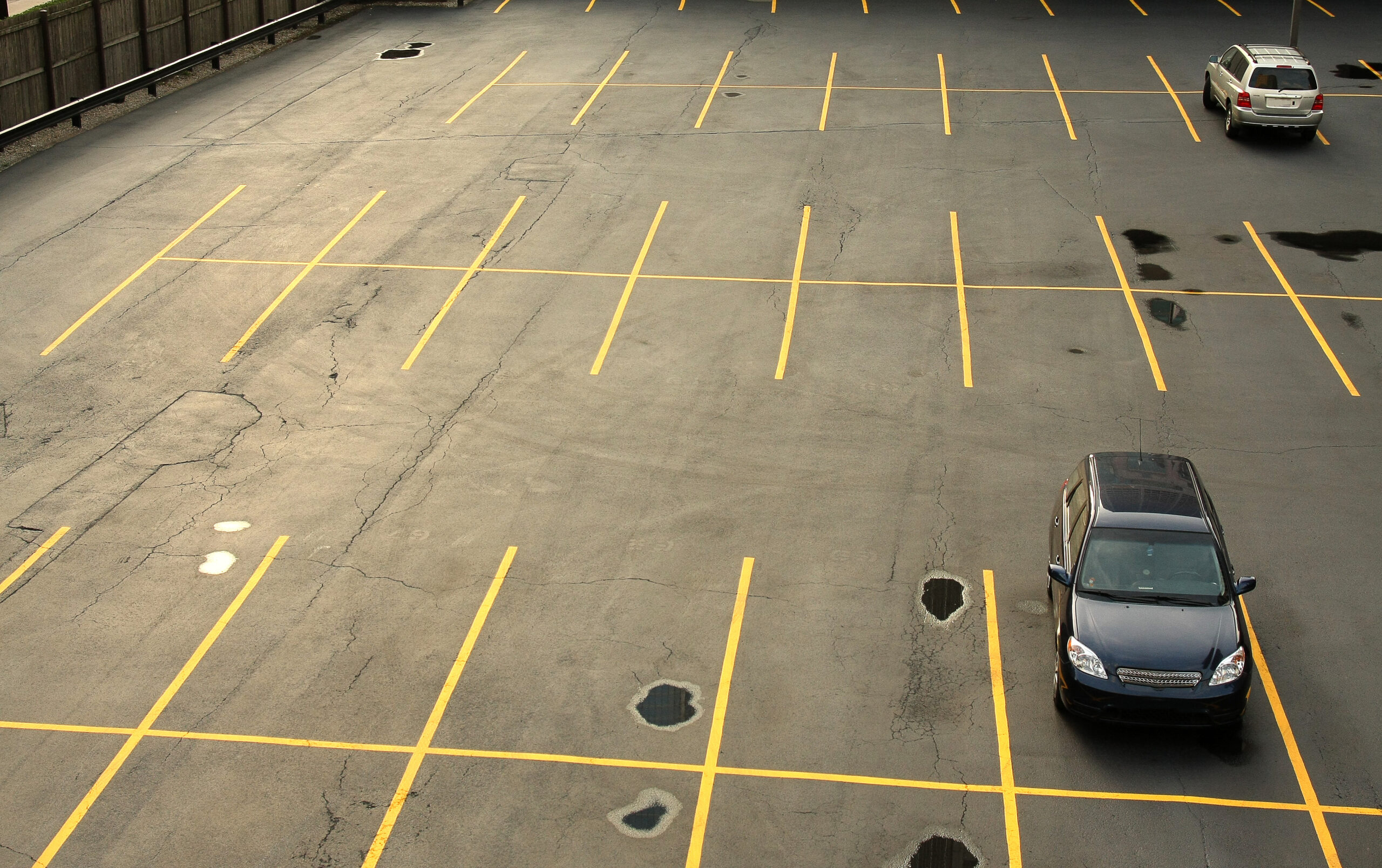 Aerial view of a mostly empty parking lot with a few cars