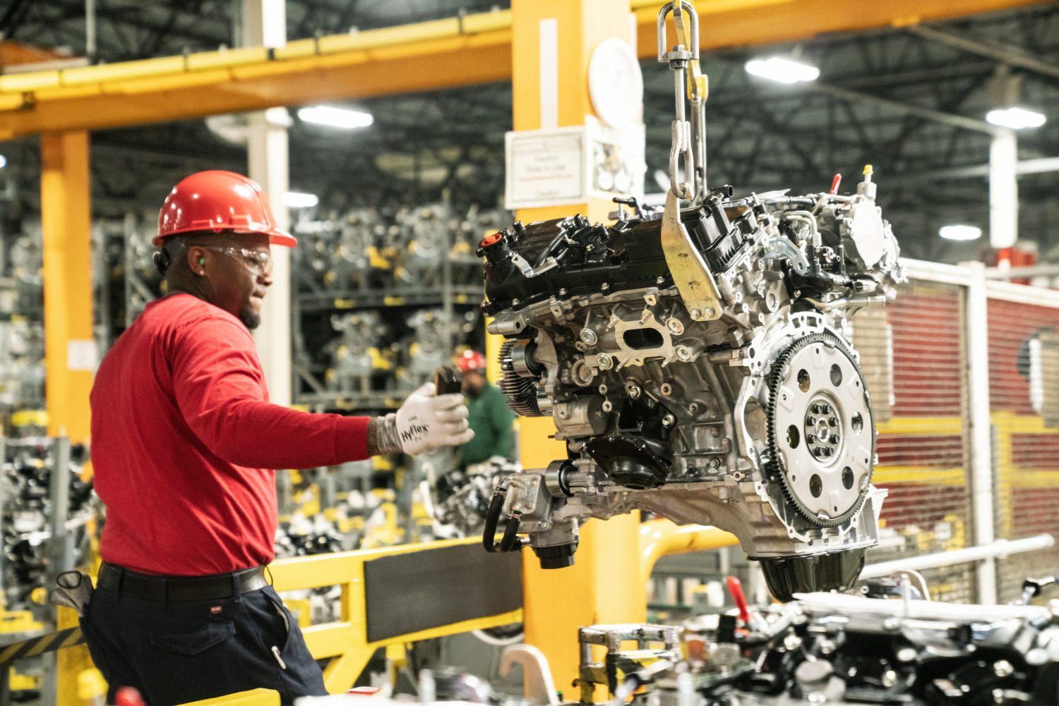 factory worker moving engine down assembly line