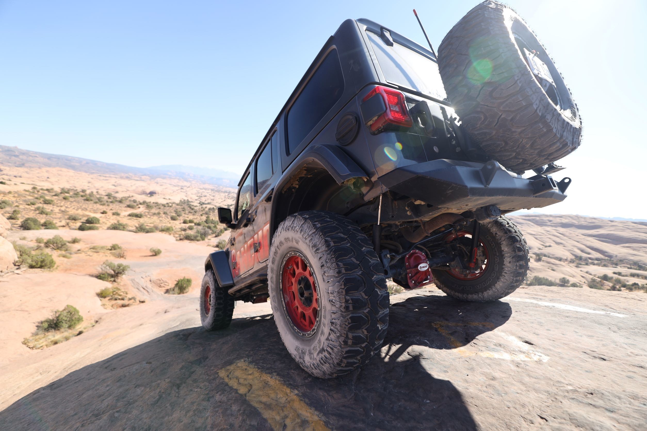 jeep driving down rock in desert 