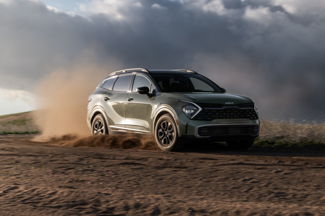 Kia Sportage driving down a dirt road and kicking up dust.