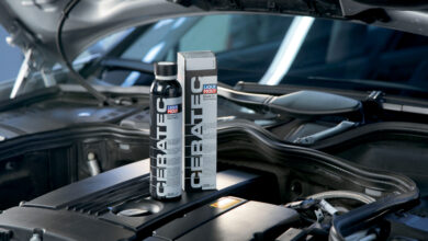 Two bottles of LIQUI MOLY Cera Tec sitting on car engine with hood propped open.