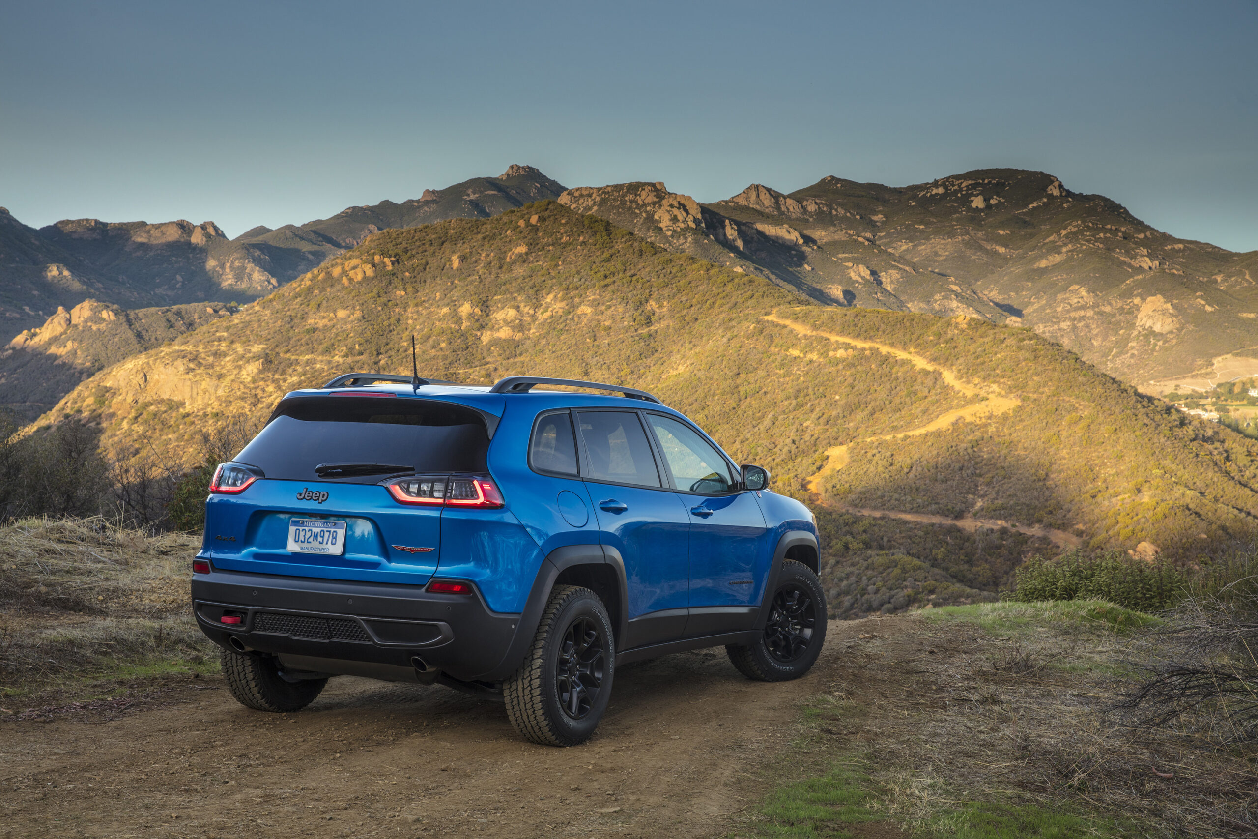 A blue 2023 Jeep Cherokee in front of a mountain landscape.