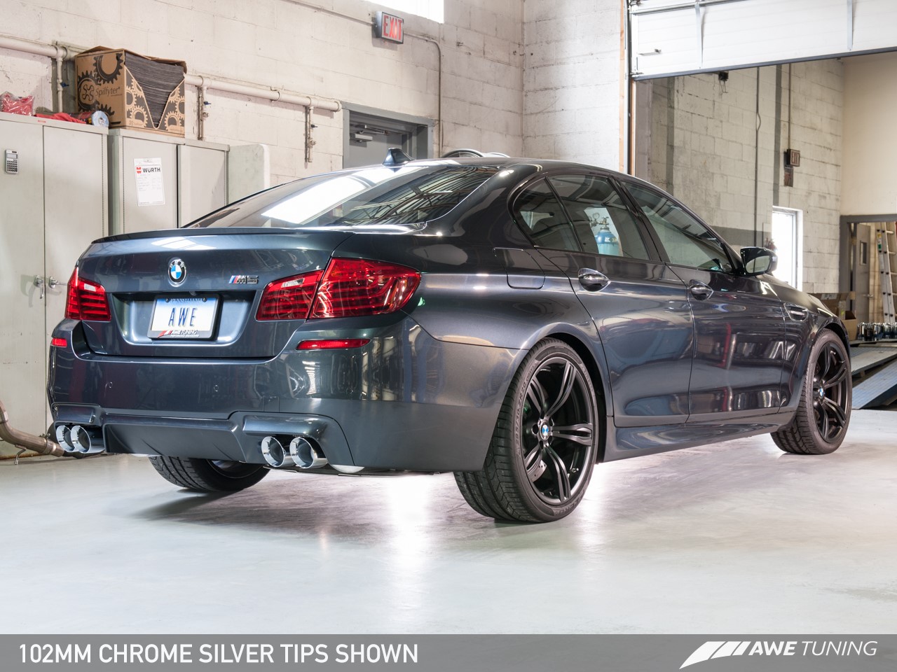 A rear view of a gray BMW M5 parked in a garage.