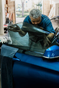 Man tinting window of blue car