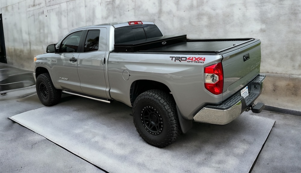 Truck Covers USA black tonneau on silver truck in front of concrete wall
