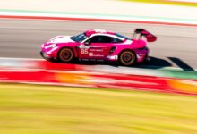 Pink Porsche race car navigates a turn