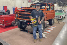 Jim McKay holding the TRIM Road Tour trophy in front of his 1972 Ford Bronco at the 75th Grand National Roadster Show