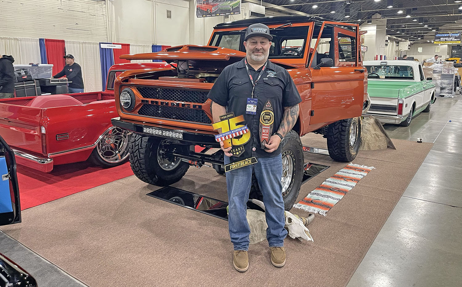 Jim McKay holding the TRIM Road Tour trophy in front of his 1972 Ford Bronco at the 75th Grand National Roadster Show