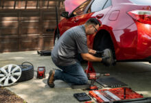 Mechanic fixing a red car in driveway