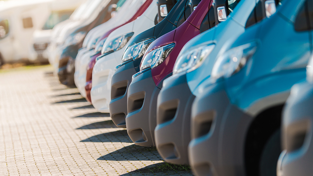 Variety of Vans Lined up in a Parking Lot During Sunny Weather