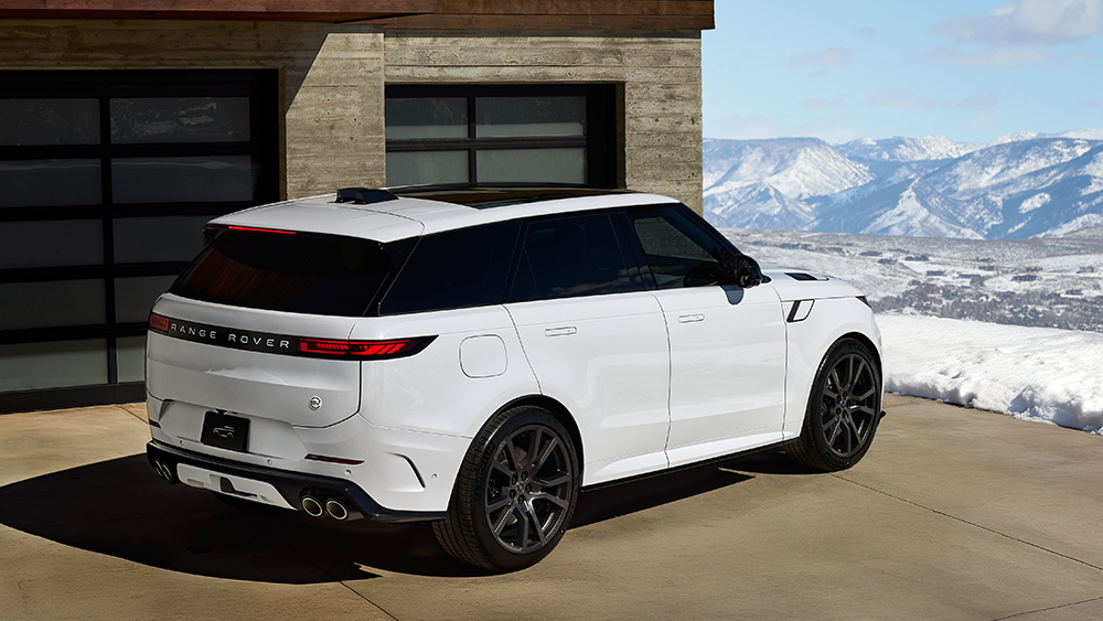 White Range Rover parked in front of Roger Rover House with mountains in background