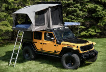 Awning and Rooftop Tent on Jeep Wrangler 4xe Sunchaser concept parked in front of tree line