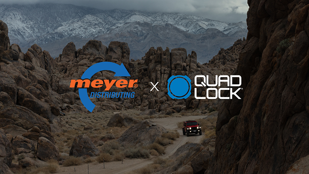 Meyer Distributing and Quad Lock logos over image of vehicle driving through mountains