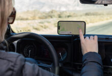 Person using smartphone mounted to dashboard