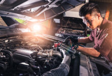 Person working on car engine with bright shop light