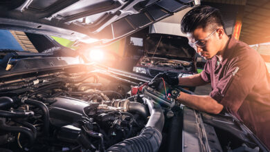 Person working on car engine with bright shop light