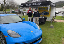 Porsche parked on grass in front of Piston Foundation tent