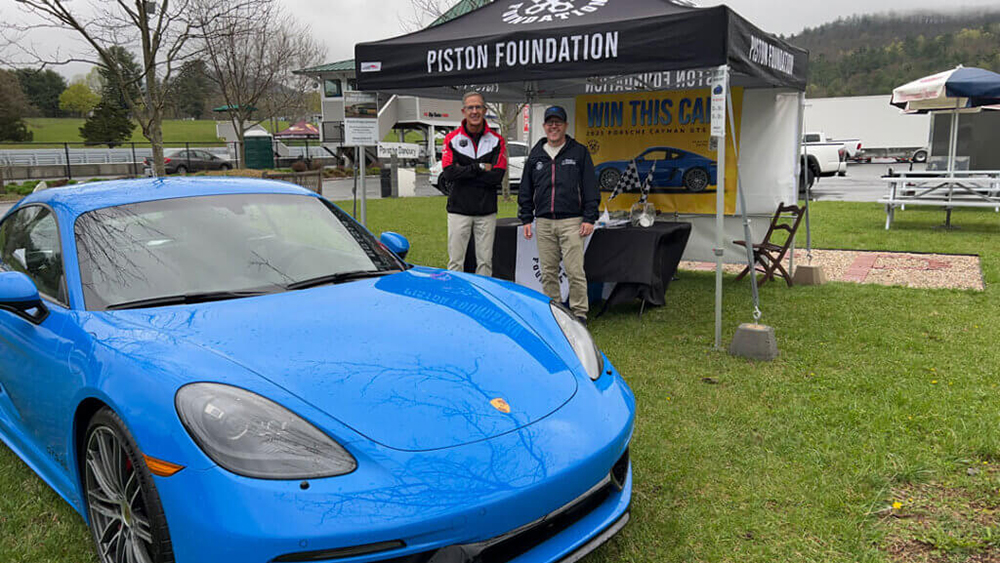 Porsche parked on grass in front of Piston Foundation tent