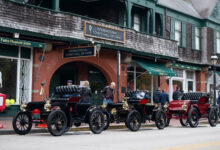 Row of brass-era cars parked on the street for the Audrain Veteran Car Tour