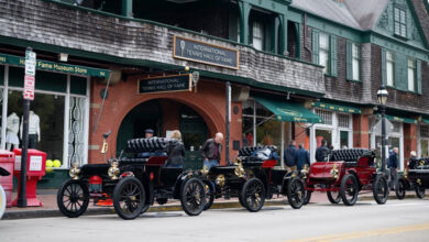 Row of brass-era cars parked on the street for the Audrain Veteran Car Tour