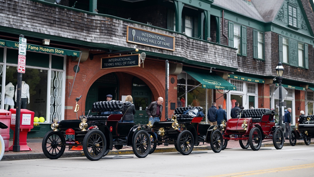 Row of brass-era cars parked on the street for the Audrain Veteran Car Tour