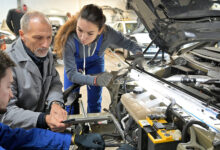Instructor with trainees working on car engine