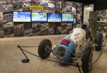Vintage race car in front of Unser Collection video wall