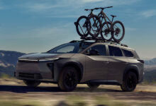 2026 Toyota 2026 bZ Woodland driving on dirt road with bicycle mounted on roof