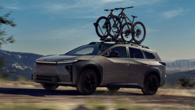 2026 Toyota 2026 bZ Woodland driving on dirt road with bicycle mounted on roof