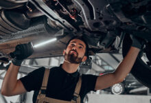 Professional auto mechanic working on the undercarriage of a car