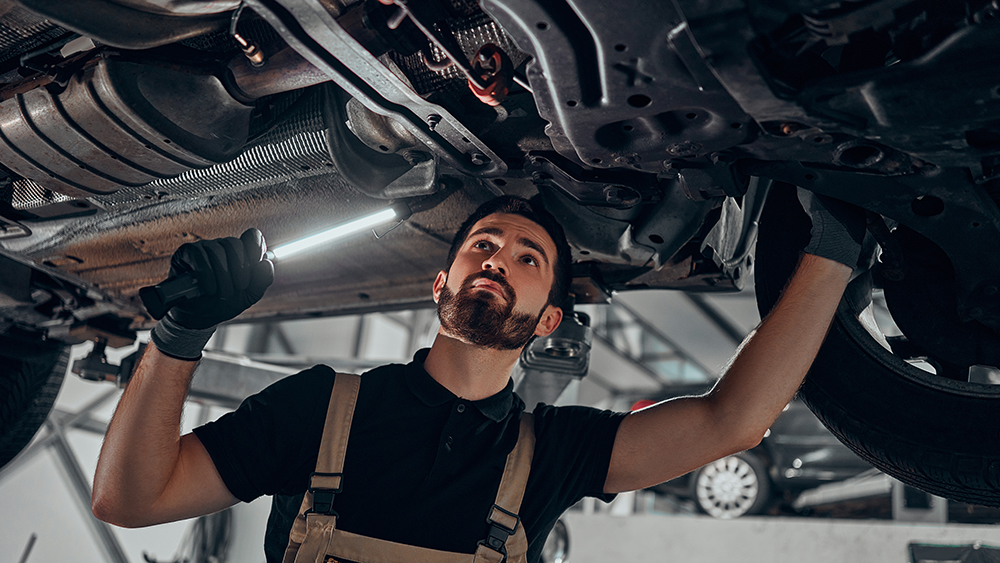 Professional auto mechanic working on the undercarriage of a car