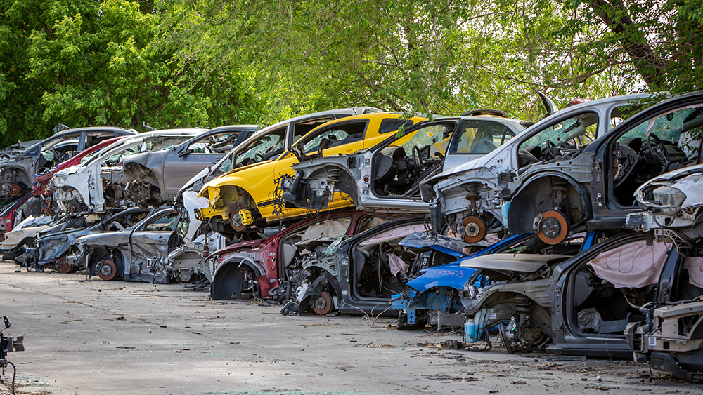 Car part salvage yard with rows of stacked wrecked cars