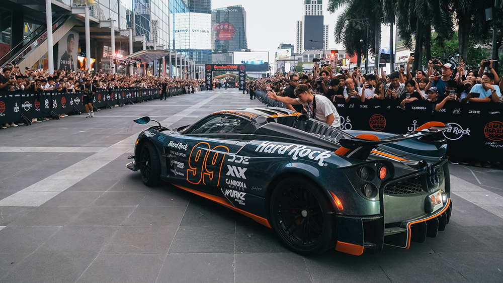 Crowds on either side of street watching Hard Rock supercar at Gumball 3000 event