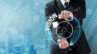 Person holding illustrated compass with the word Vision and an arrow