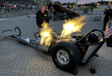 Person watching hot rod with flames shooting out