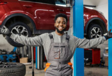 Smiling auto mechanic with opened arms and looking at camera