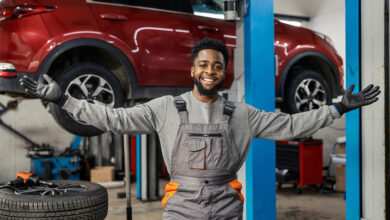 Smiling auto mechanic with opened arms and looking at camera